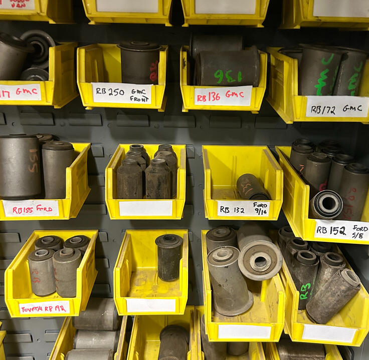 Leaf spring bushings, centre bolts, inserts, and suspension hardware organized in inventory bins at Standard Auto Spring Works.