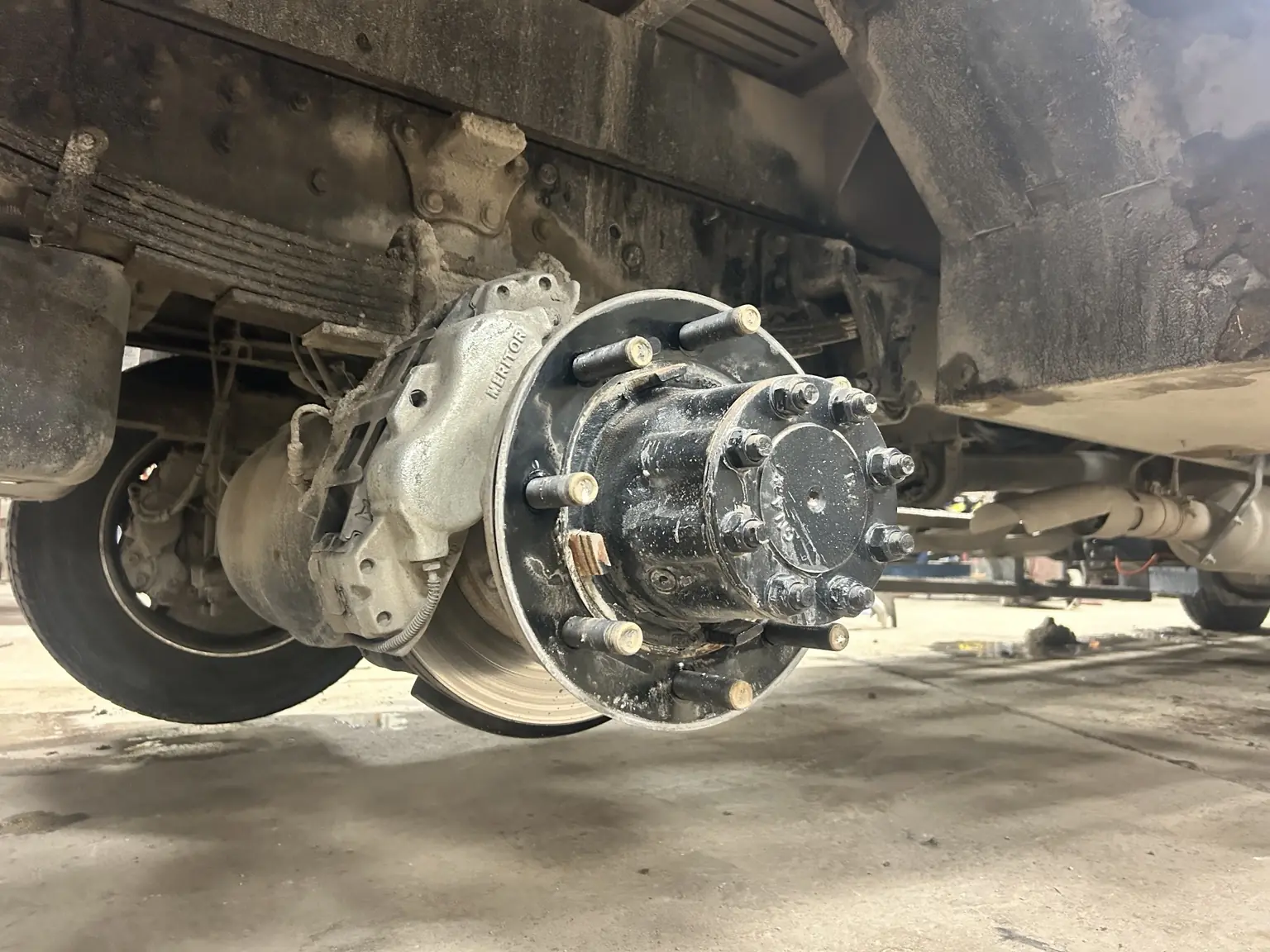 Heavy commercial truck wheel end and leaf spring suspension exposed in the shop