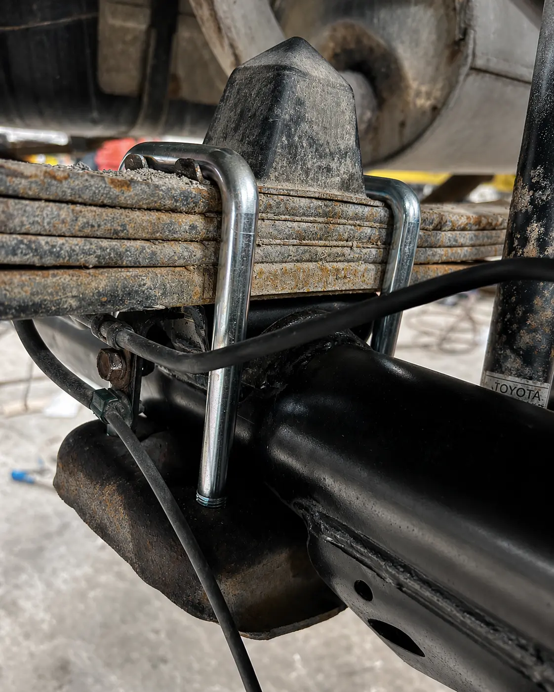 New custom U-bolts installed around a leaf spring pack and axle