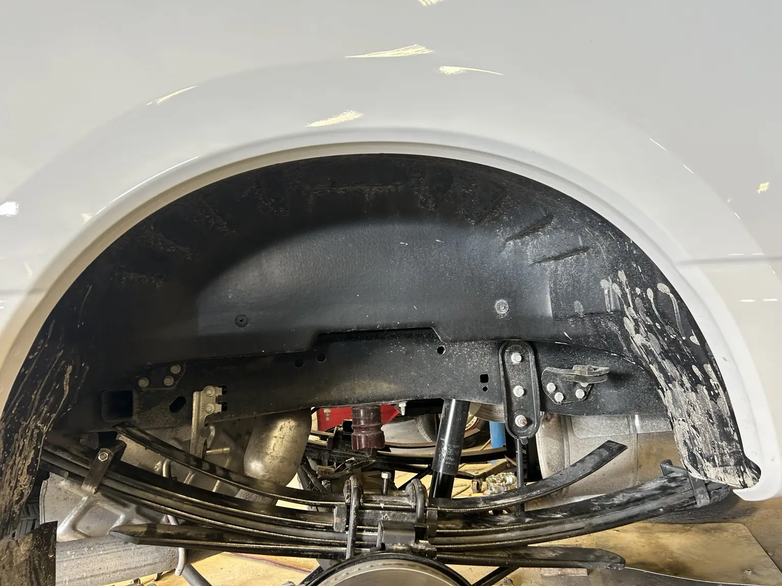 Leaf spring, shock and mounting hardware visible inside a truck wheel well